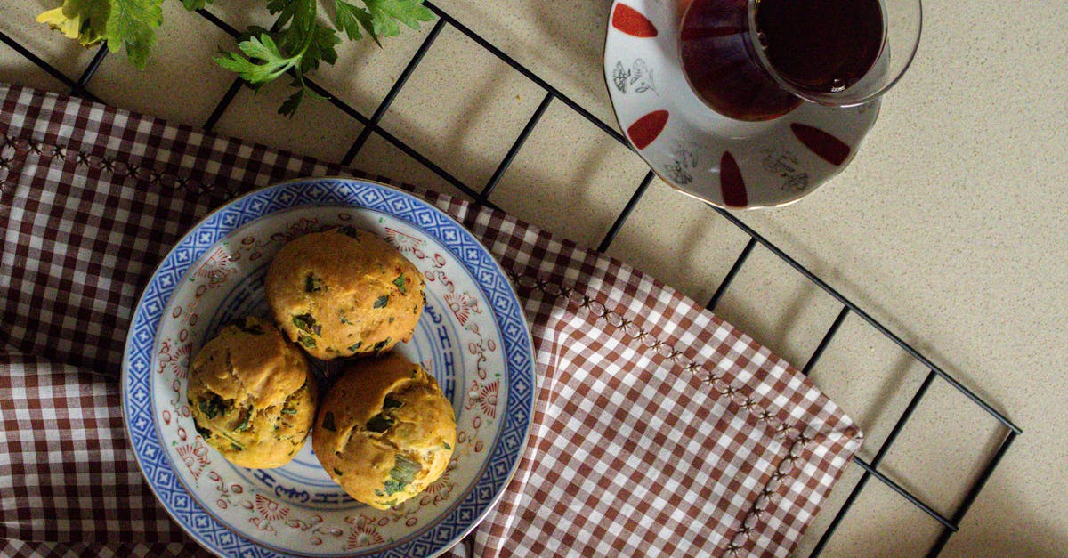top view of freshly baked herb muffins served with tea on a checkered cloth setting
