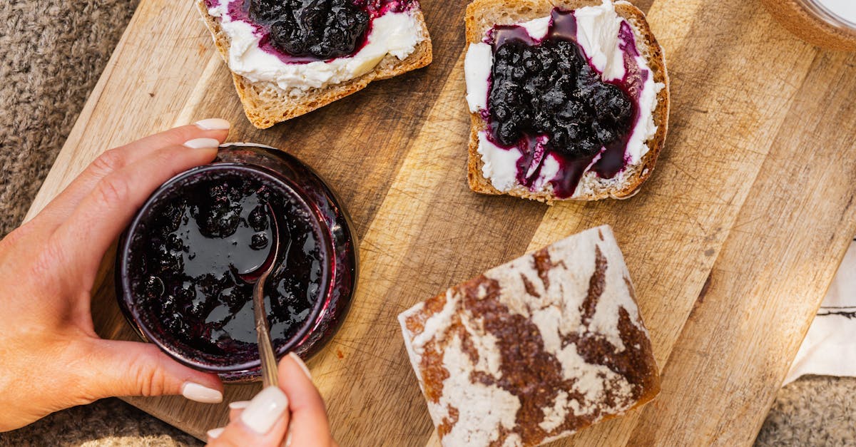 top view of homemade blueberry jam spread on bread with hands holding the jar perfect for breakfast