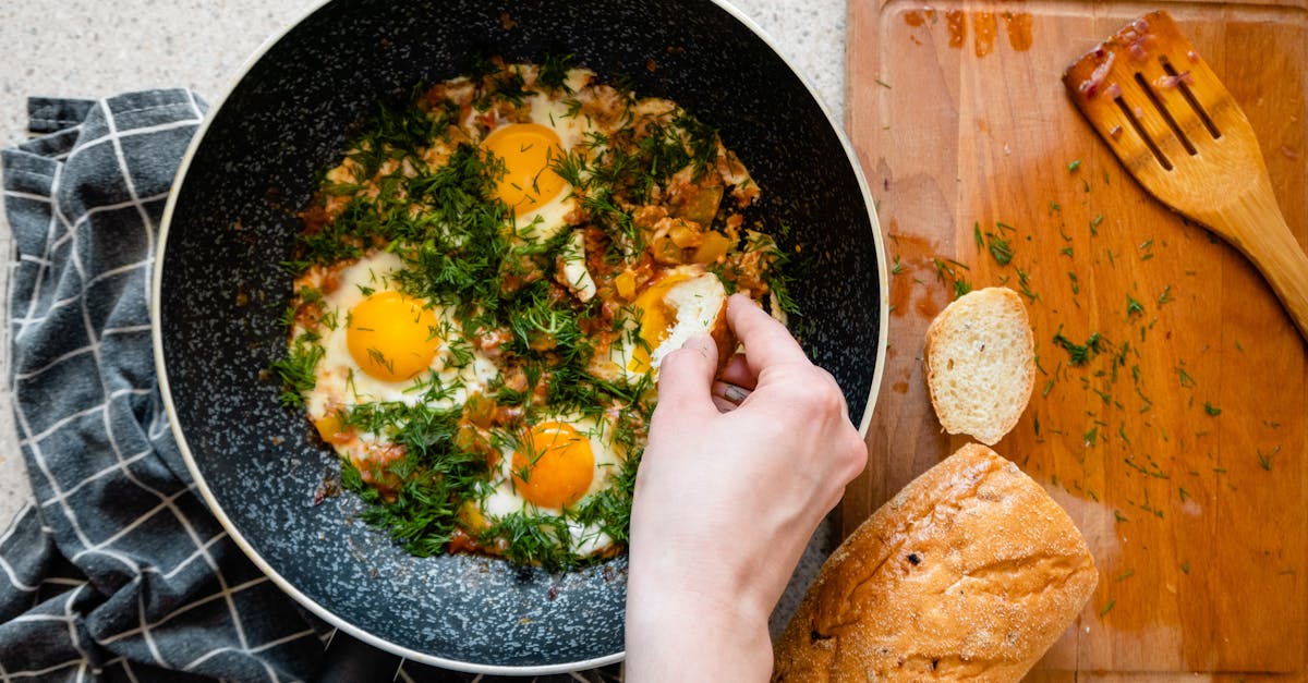 top view of shakshouka in a frying pan with bread on a wooden chopping board