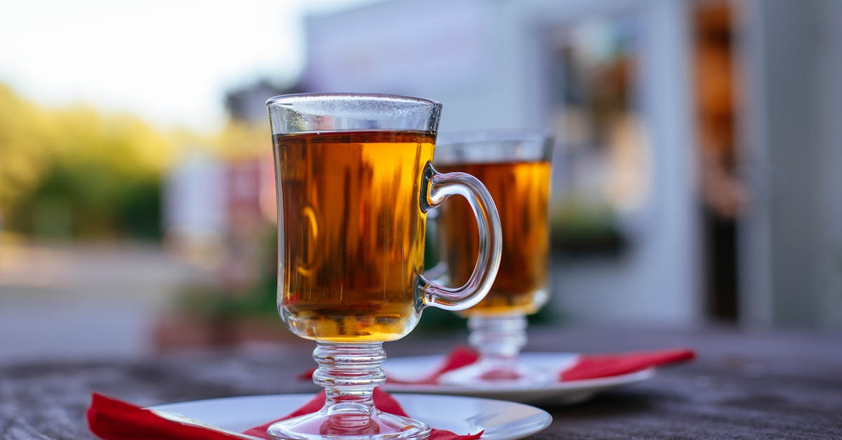 two glass mugs with amber hot drinks on a wooden table outdoors creating a warm and inviting atmosp