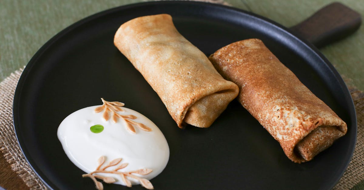 two savory pancakes served with a dollop of cream on a black plate ready to enjoy