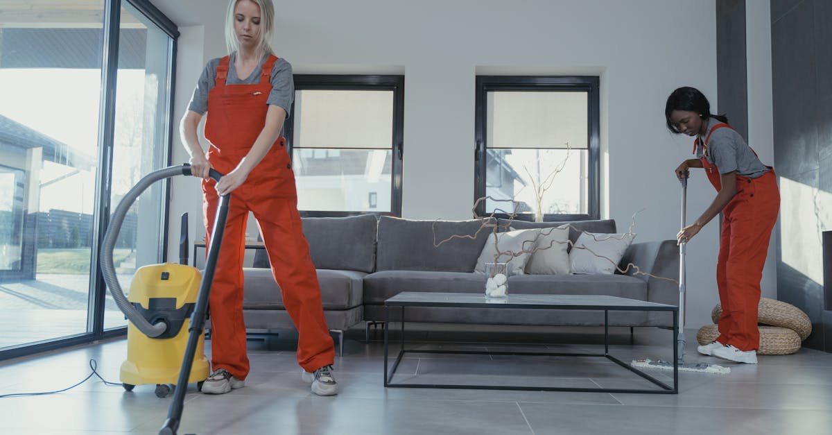 two women in red overalls vacuuming and sweeping a modern living room