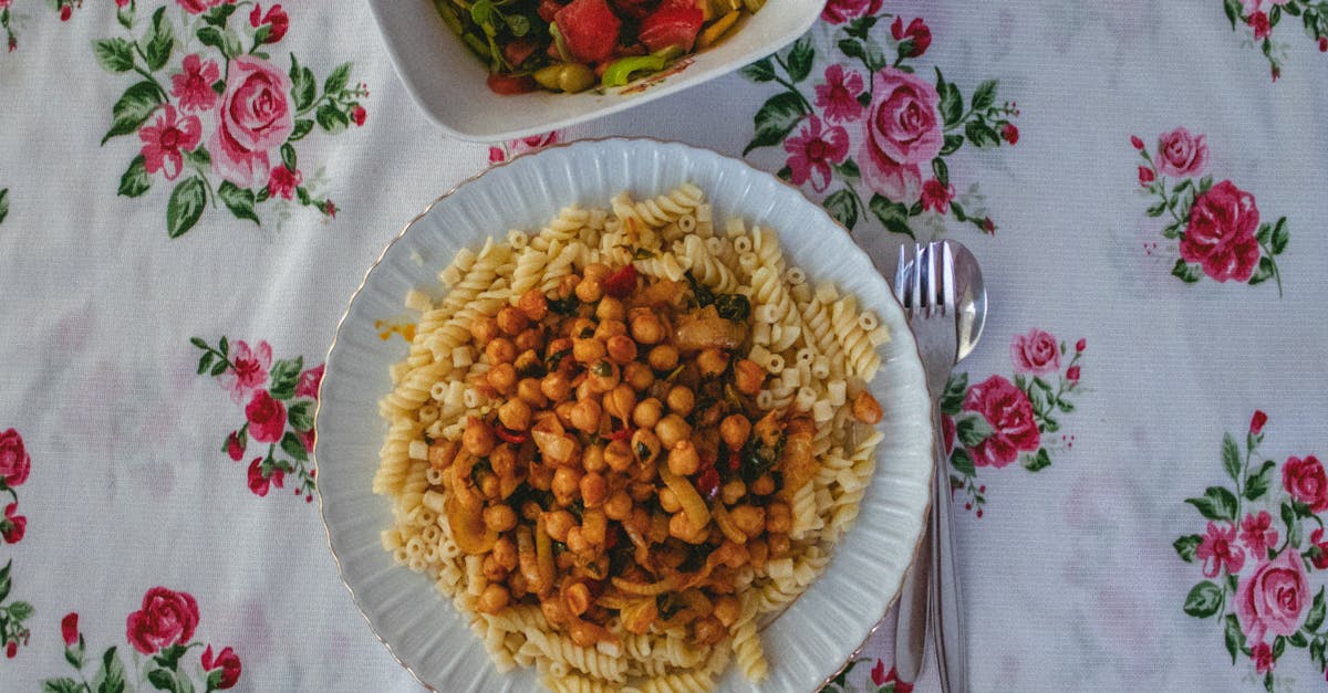 vibrant pasta dish served with a fresh vegetable salad on a floral tablecloth