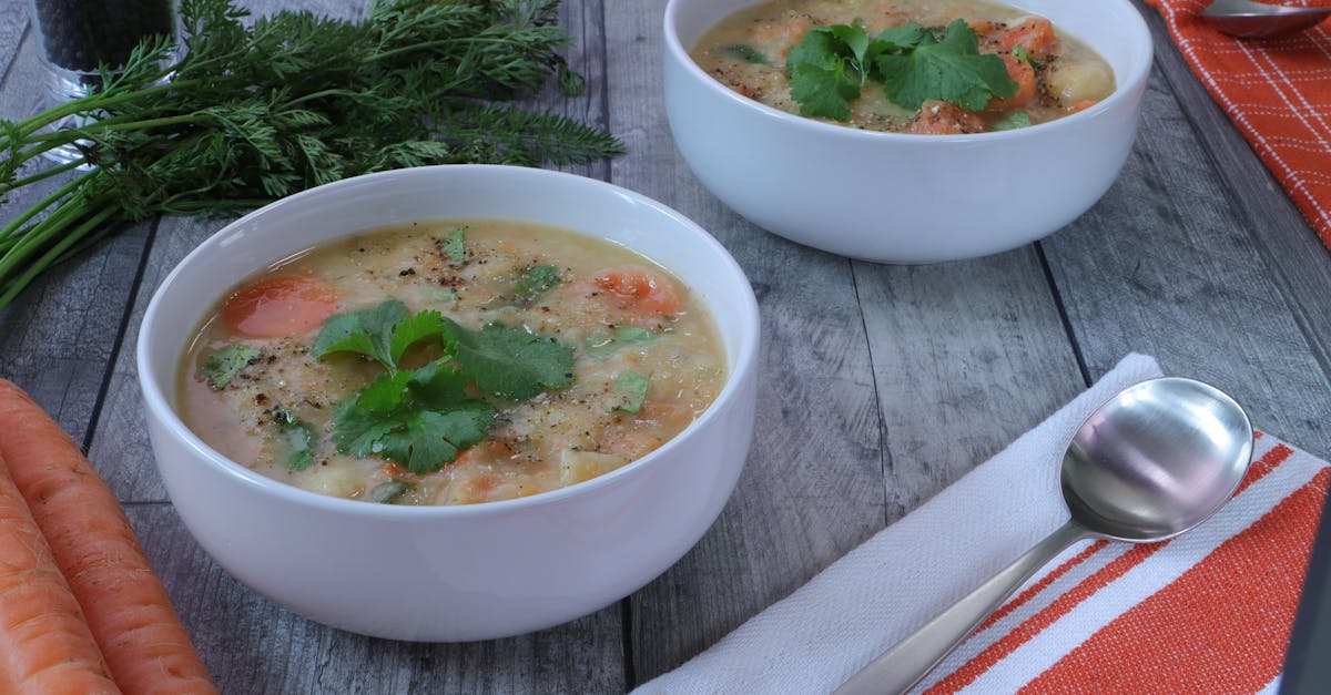 white bowls filled with hearty homemade vegetable soup garnished with cilantro
