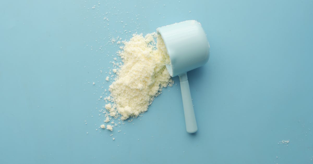 white powder spilled from a scoop on bright blue background clean and minimalistic food photo