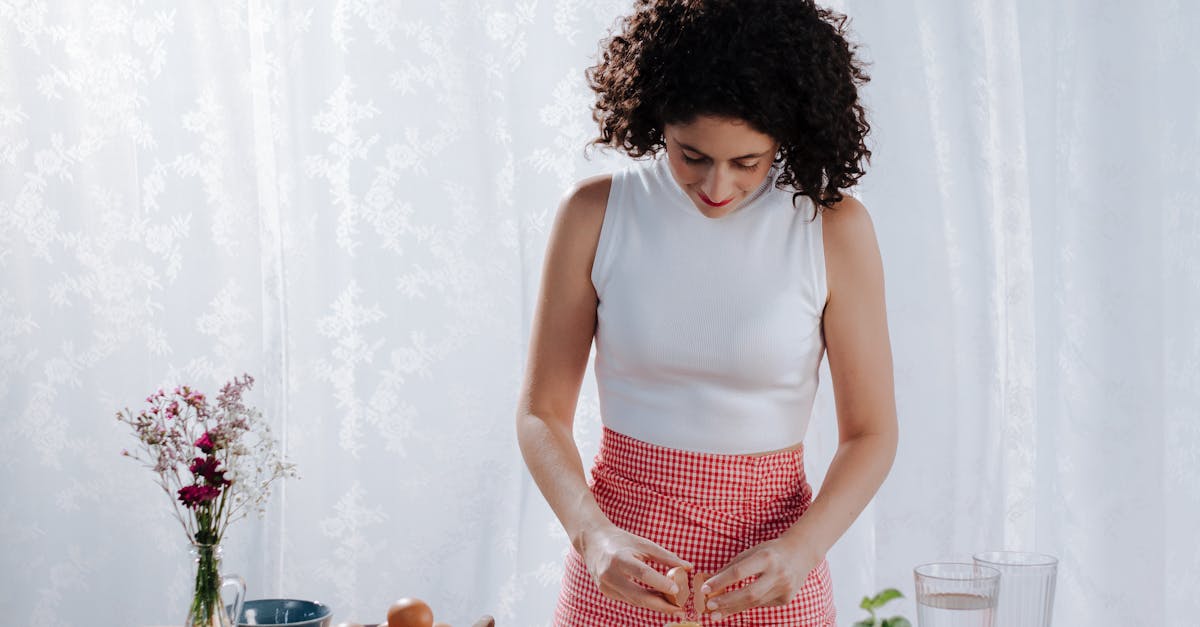woman breaking an egg into a flour mound preparing italian cuisine indoors