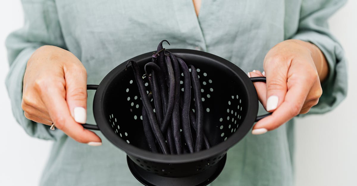 woman holding a black colander with fresh black beans emphasizing cooking and food preparation 7